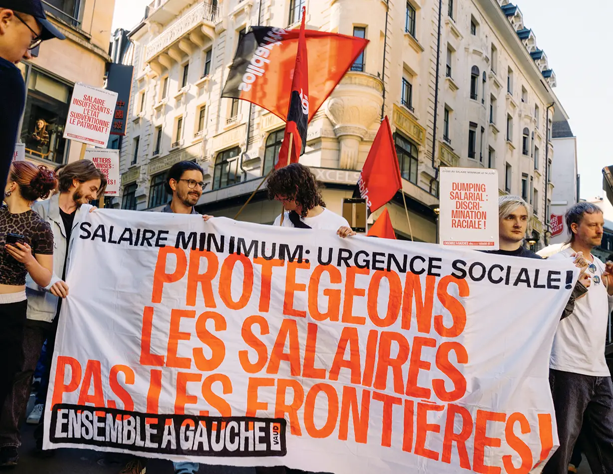 Pancarte “salaire minimum: urgence sociale: protégeons les salaires pas les frontières!”